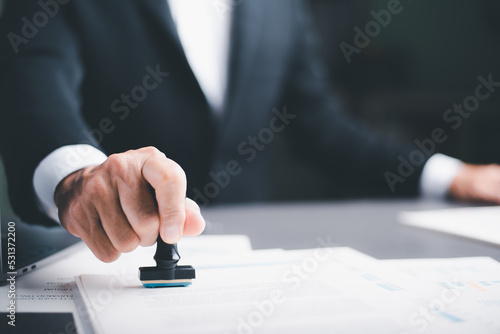 business people stamp On the contract documents at the desk, the concept of confirmation or approval of the agreement, the application authorization authority, the bank loan documents through support. photo