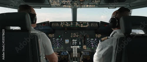 Commercial aircraft pilots adjusting flight parameters of the plane during the flight at high altitude. View from inside the cabin. Real aircraft, daytime shot