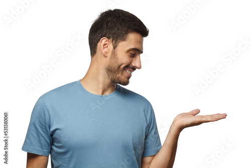 Young smiling man wearing casual blue t-shirt and demonstrating something on right with palm photo