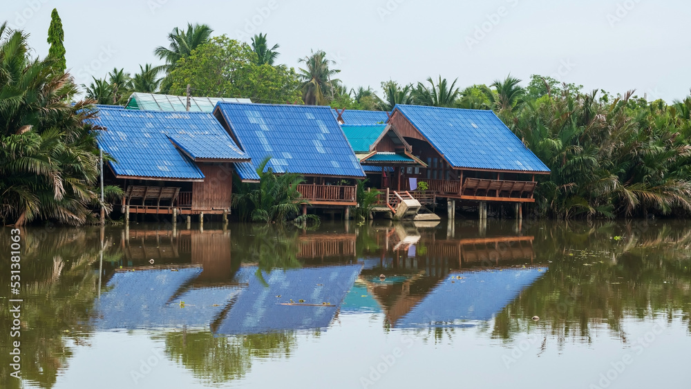 Traditional Thai wooden homes with Nipa palms growing by river Traditional Thai wooden homes with Nipa palms growing by river