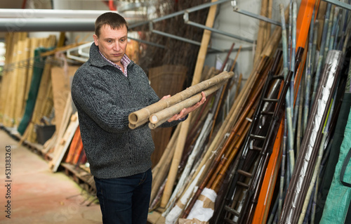 Man chooses decorative fence from bamboo in store. High quality photo