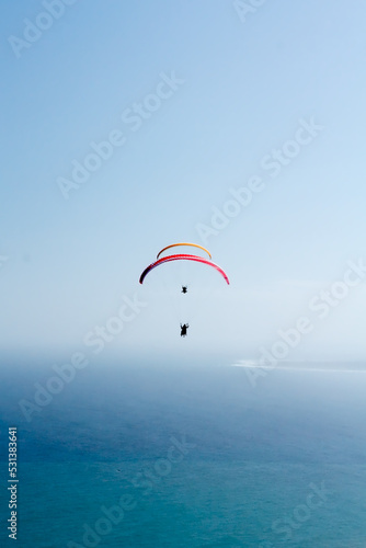 Paragliders in unison against a clear sky