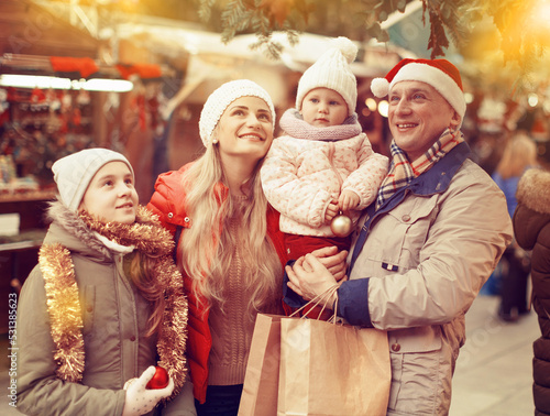 Family portrait of smiling parents with their two nice daughters at Christmas fair