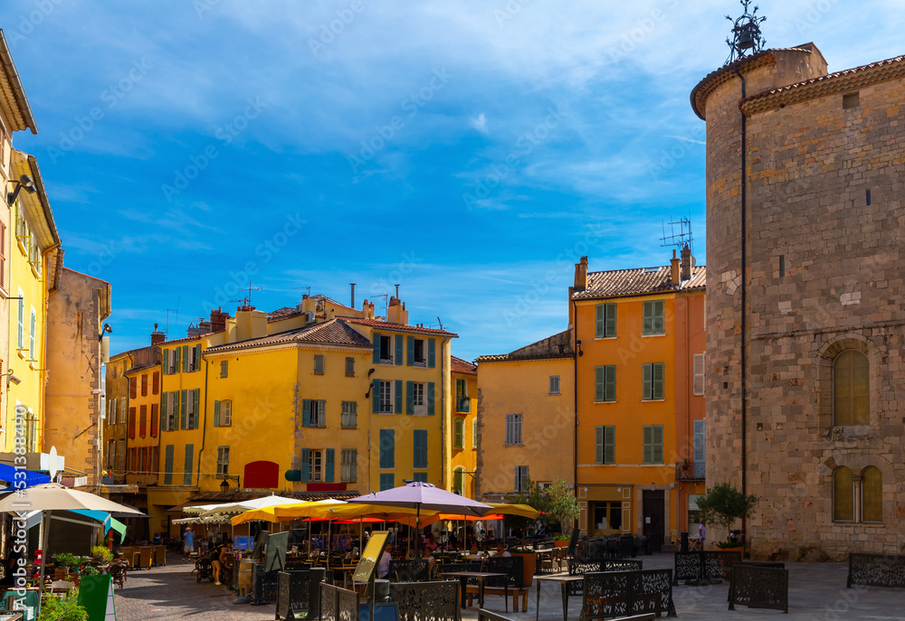 Scenic view of Hyeres townscape on sunny autumn day with cosy outdoor cafe near ancient Knights Templar tower in small square in old center, France