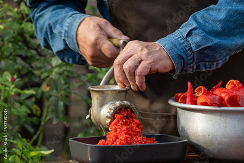 Making vegetable sauce. Mechanical grinding of paprika, sweet bell peppers and hot pepper chilli. Preparation of homemade sauce. Salad with red peppers. Healthy organic food concept Close up outdoors