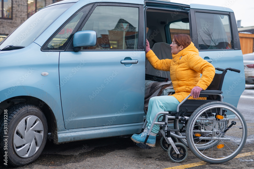 Caucasian woman in a wheelchair gets into the car. Caucasian woman in a wheelchair gets into the car.