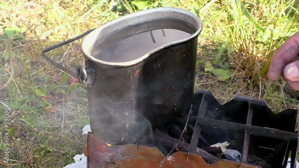 A camp pot with water is boiling over a fire. The food of nature-traveling hikers. A camp pot with water is boiling over a fire. The food of nature-traveling hikers.