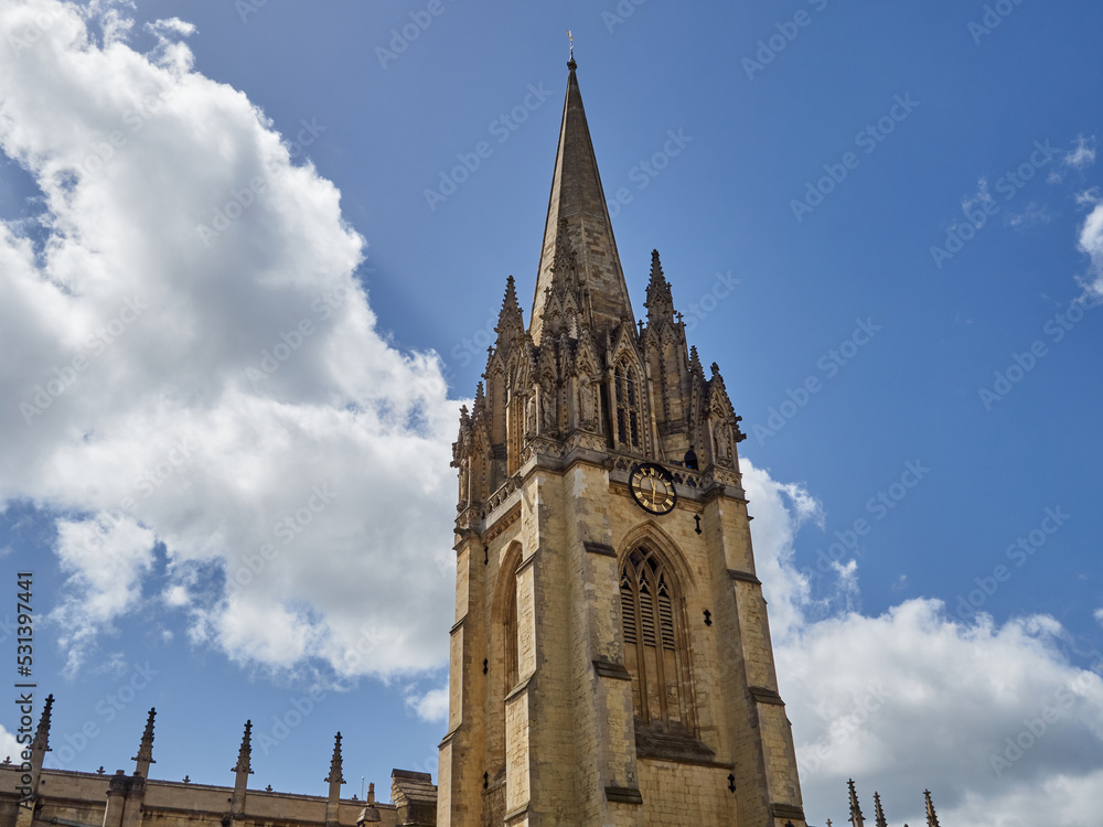 Tower of The University Church of St Mary the Virgin with a decorated spire with pinnacles and statues in a sunny day with fluffy white clouds. Oxford, England, UK Europe