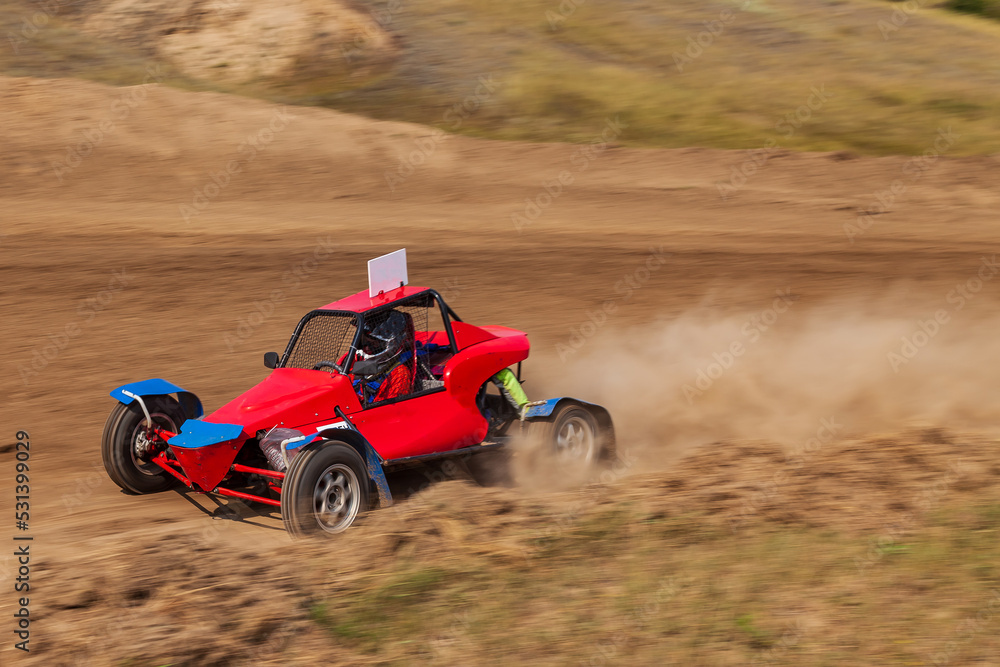 A small sports blurred buggy on a rally competition track during weekend training on a warm summer day. A small sports blurred buggy on a rally competition track during weekend training on a warm summer day.