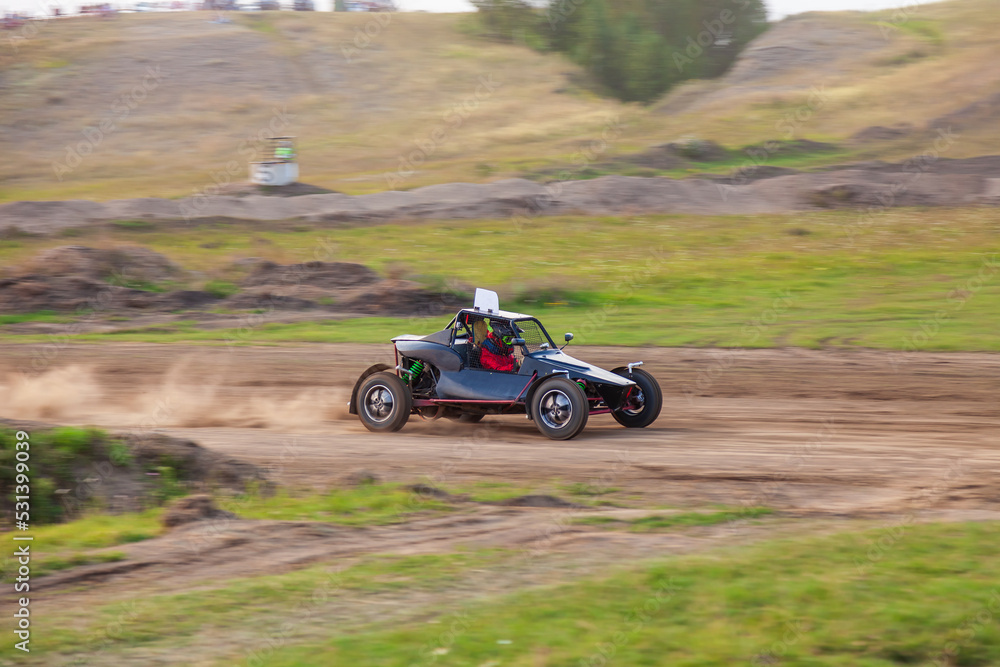 A small sports blurred buggy on a rally competition track during weekend training on a warm summer day.
