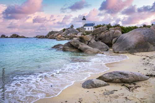 The Pontusval lighthouse, located on a rocky point in northern Finistere in Brittany, overlooks a sea of transparent turquoise waters during sunrise photo