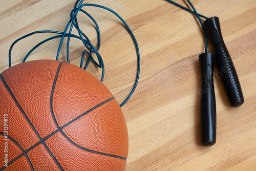 Sports jump rope and a basketball ball close-up on a wooden parquet.Healthy lifestyle. Morning exercises, physical culture, training. © Александр Ланевский