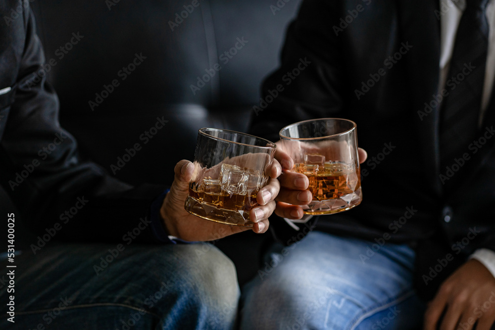 Close-up of serious businessman holding a glass of whiskey bar rest ideas and drinking alcohol