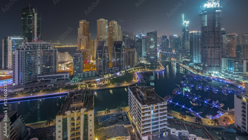 Dubai Marina with several boat and yachts parked in harbor and skyscrapers around canal aerial all night timelapse. Dubai Marina with several boat and yachts parked in harbor and skyscrapers around canal aerial all night timelapse.