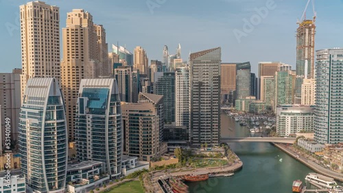 Dubai Marina with several boat and yachts parked in harbor and skyscrapers around canal aerial timelapse.
