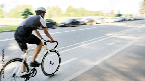 A blurry photo in motion. A cyclist and his bike, rides very fast on the road in the city.