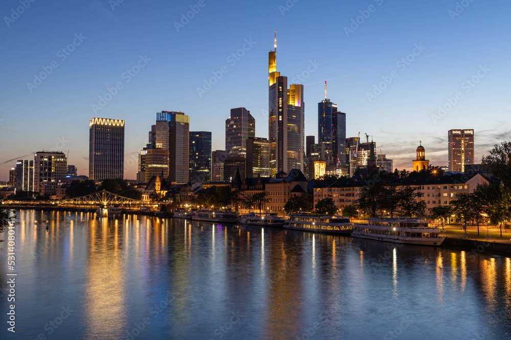 Frankfurt skyline and Eiserner steg bridge at night with reflection in the Main river in the foreground, taken from the Alte Brücke bridge