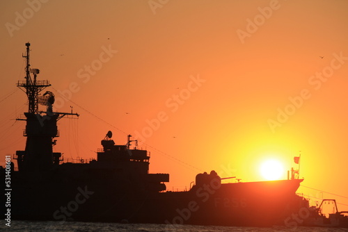 Sunset over the silhouette army ship