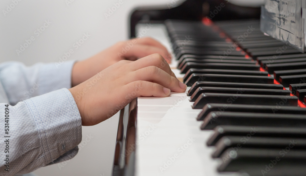 Little talent child sitting at grand piano playing classical music. Boy pianist learning to be skill keyboard instrument musician. Happy kid has fun leisure activity practicing piano key melody hobby.