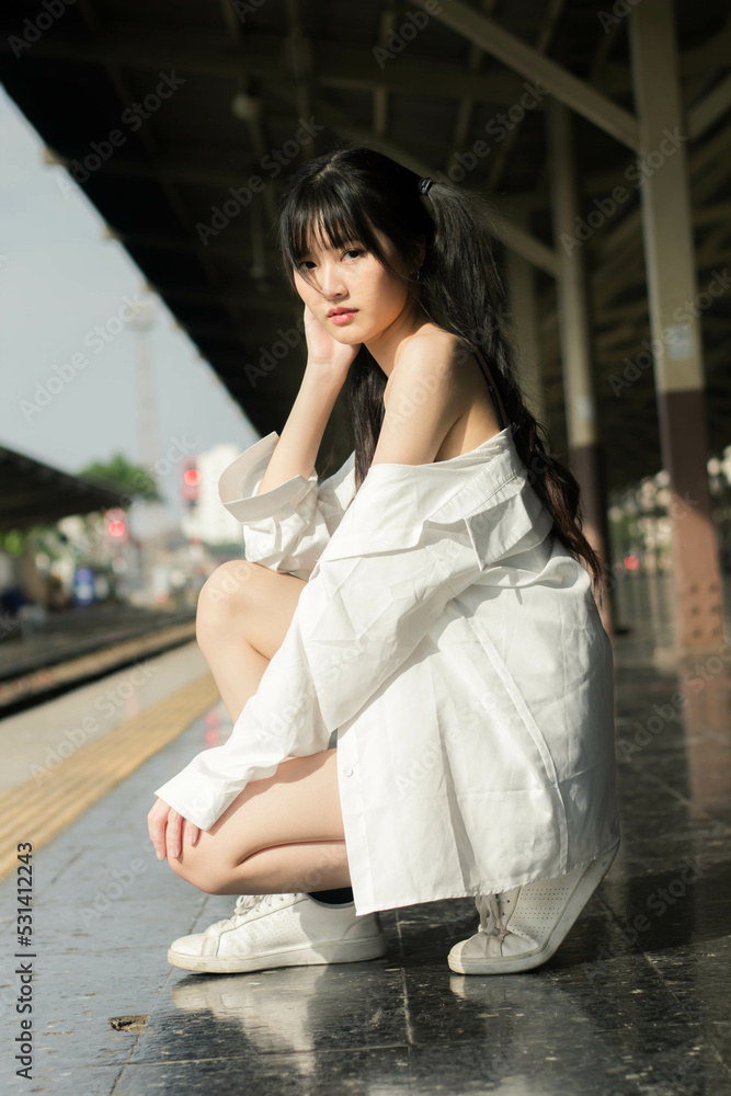 Fototapeta premium Portrait of thai japan adult beautiful girl white shirt blue jeans relax time, train station fashion