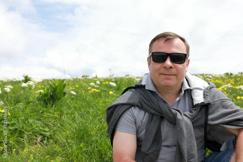 Man sitting on meadow on Lago-Naki plateau in summer Man sitting on meadow on Lago-Naki plateau in summer