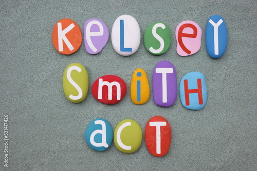 Kelsey Smith Act, law name composed with multi colored stone letters over green sand photo