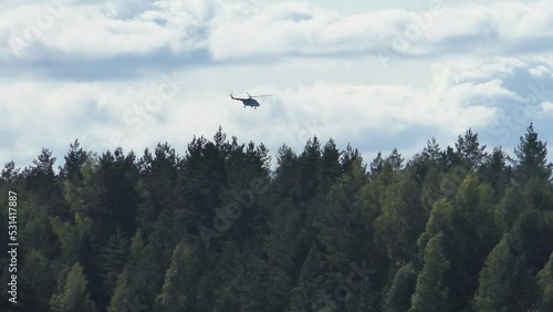 A rescue helicopter is flying over the forest. Search flying transport observer inspects wildlife.