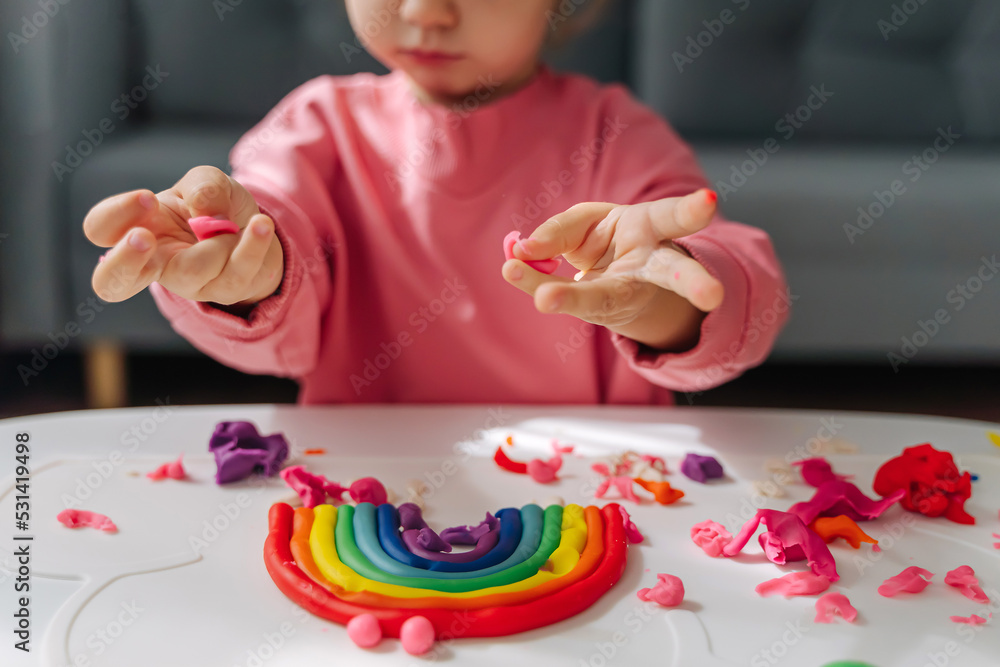 Child hands creating rainbow from play dough for modeling. Art Activity for Kids. Fine motor skills. Sensory play for toddlers. - obrazy, fototapety, plakaty 