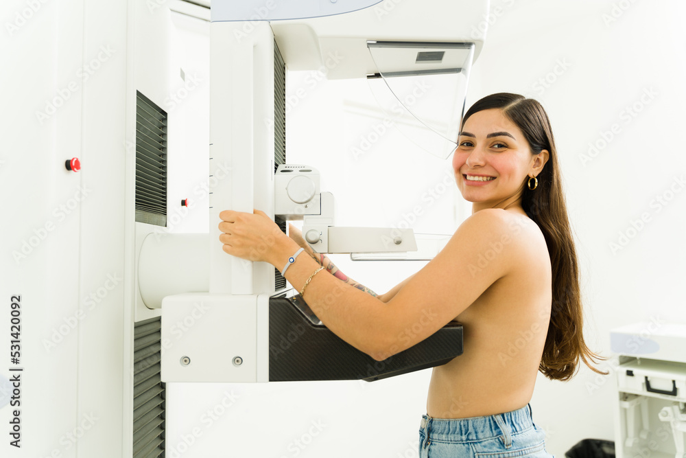 Portrait of a happy hispanic woman at the imaging diagnostic lab smiling while getting a mammogram during a breast cancer awareness program Portrait of a happy hispanic woman at the imaging diagnostic lab smiling while getting a mammogram during a breast cancer awareness program