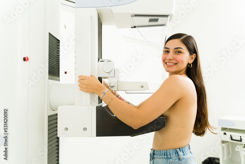 Portrait of a happy hispanic woman at the imaging diagnostic lab smiling while getting a mammogram during a breast cancer awareness program photo