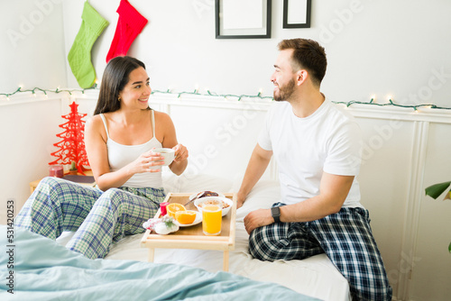 Happy couple eating breakfast in bed on a beautiful morning