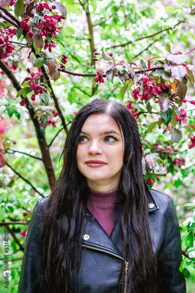 Lifestyle portrait of young beautiful woman on background of red and white apple tree flowers in rainy weather. Lifestyle portrait of young beautiful woman on background of red and white apple tree flowers in rainy weather.
