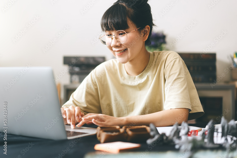 Asian woman using laptop for half role playing tabletop and board game with online friends Asian woman using laptop for half role playing tabletop and board game with online friends