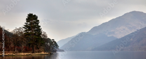 On a late March evening, gentle rain begins to fall on the reflective still surface of Loch Eck. Argyll and Bute