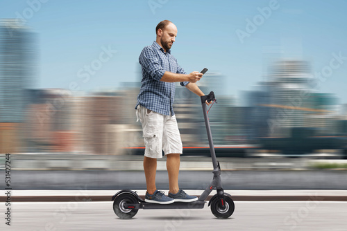 Schilderij op canvas Man using a smartphone while riding an electric scooter