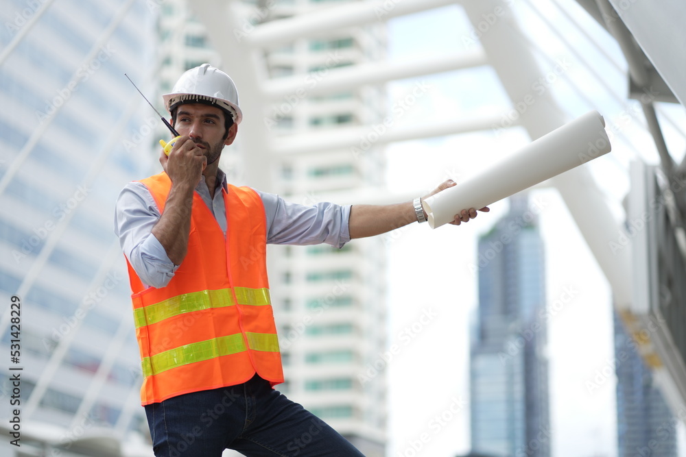 Architect or engineer with blueprints. Cauacsian Engineer checking plan on construction site. modern structure.