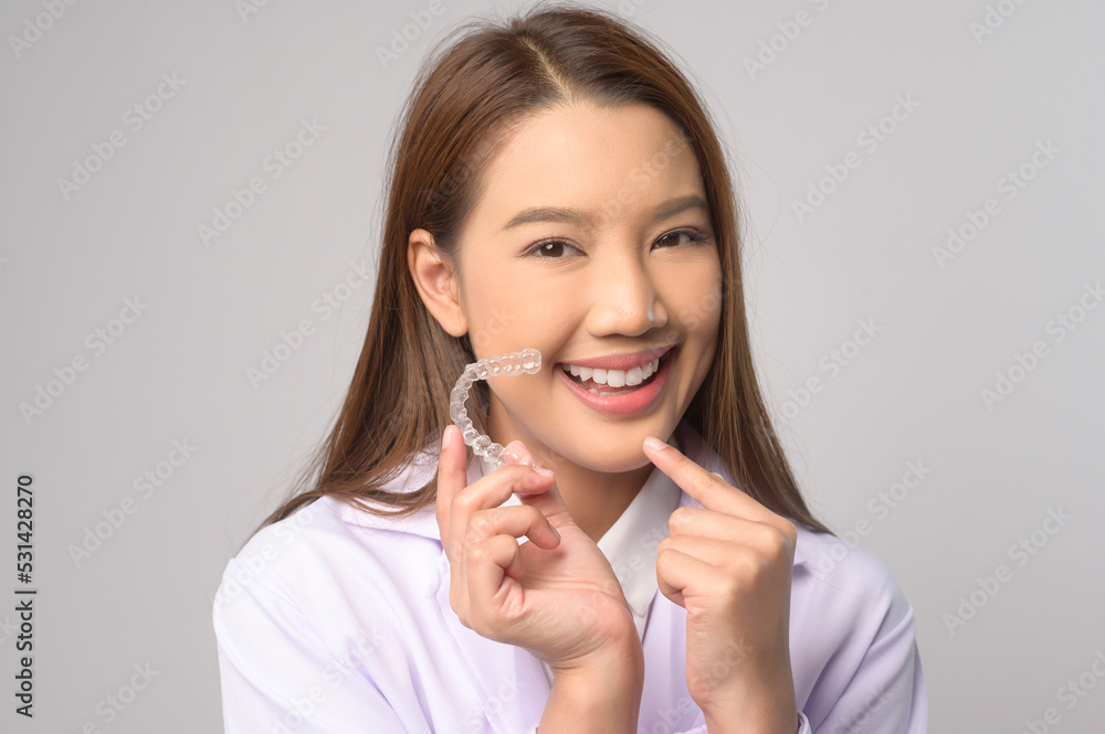 Young female dentist holding invisalign braces over white background studio, dental healthcare and Orthodontic concept.. Young female dentist holding invisalign braces over white background studio, dental healthcare and Orthodontic concept..