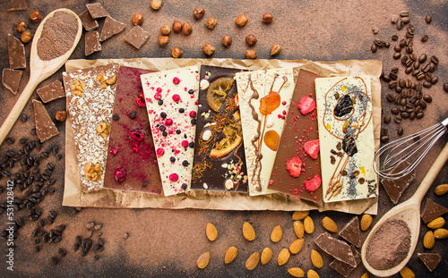 Handmade chocolate with berries, nuts, dried fruits and ingredients for making chocolate on a dark background. Black and white chocolate. Chocolate bars. Close-up