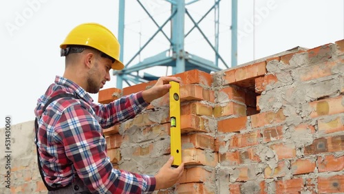 Worker control brick wall using level tool photo