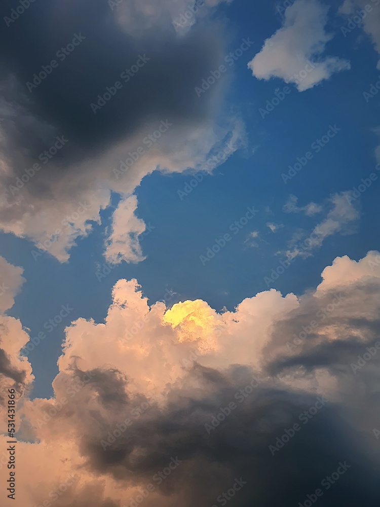 Thunderstorm clouds sunlit with a golden light like coming out of heaven. Dreamlike sky, vertical celestial background