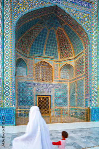 Woman with white burka (burqa) and child walking in front of the Timurid Blue Mosque in Mazar-i-Sharif (Mazar-e Sharif), also called Shrine of Hazrat Ali, Balkh Province, Northern Afghanistan photo