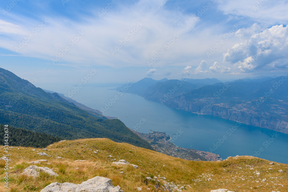Amazing view of the Garda lake in Italy, seen from the top of the mountain Monte Baldo. The lake stretches far out in the horizon. The city of Malcesine can be seen at the foot of the mountain