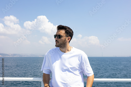 Young, handsome man with sun glasses by sea. Summer vacation, freedom and holiday concept. 