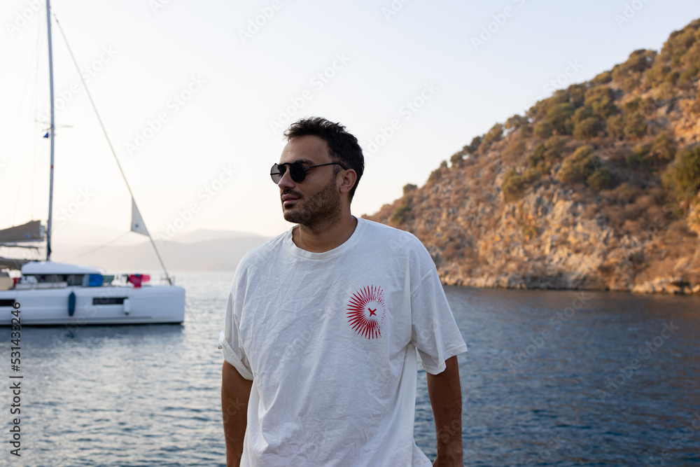 Young, handsome man with sun glasses on sailing boat. Summer vacation. 