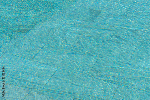 Swimming pool water background with caustic ripple. Aquatic surface with waves backdrop.