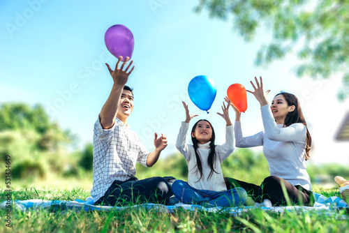 Happy asian family in the garden, Father, Mother and doughter. They are having fun playing balloon in holiday.