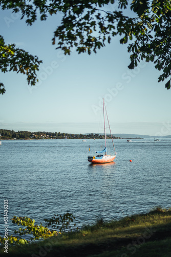 kleines rotes segelboot ankert auf dem wasser in der abendsonne in Norwegen