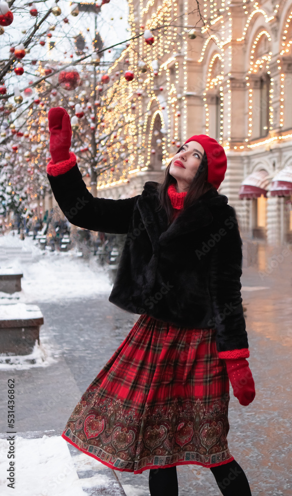 beautiful girl in a red beret and mittens in winter on New Year's street.