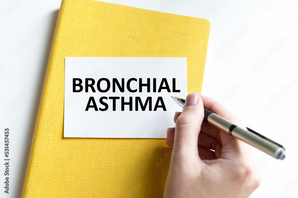 BRONCHIAL ASTHMA text on a card against a background of yellow blaknot on the table BRONCHIAL ASTHMA text on a card against a background of yellow blaknot on the table