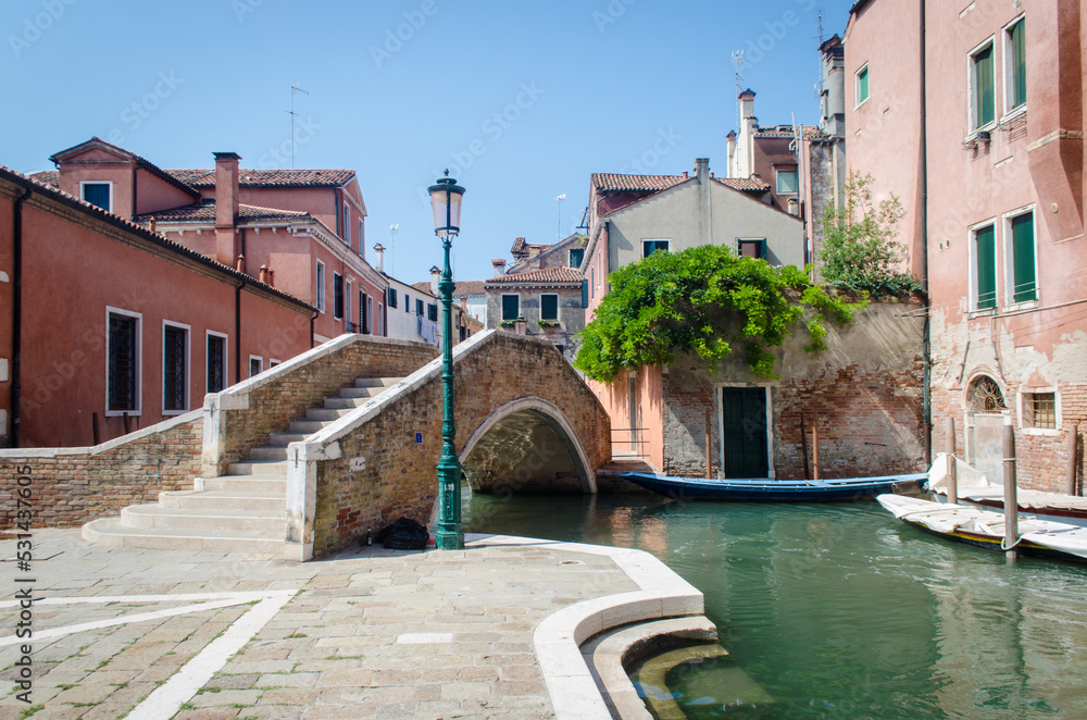 Uno scorcio di Venezia con un canale, un ponte e un lampione in una giornata di sole senza nuvole